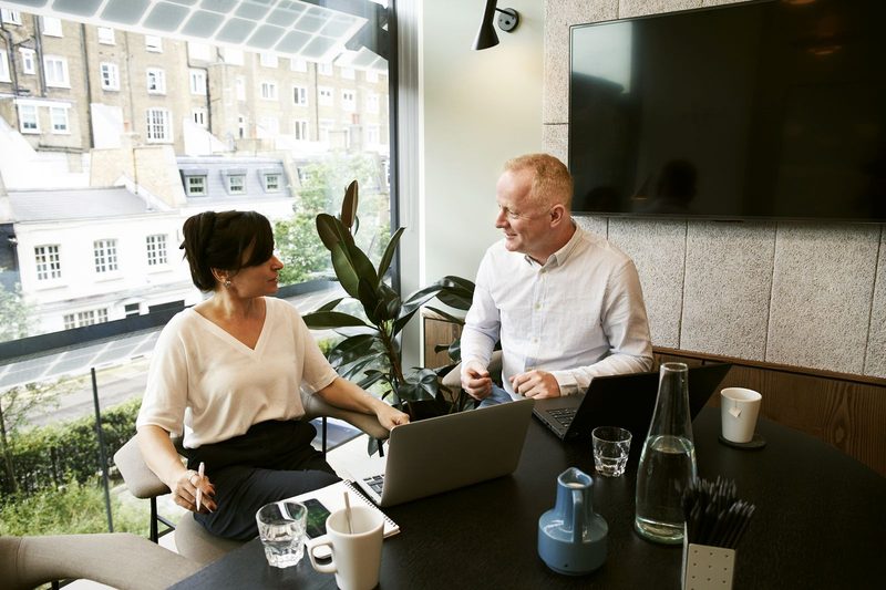 Two colleagues talking across a desk during a hiring conversation