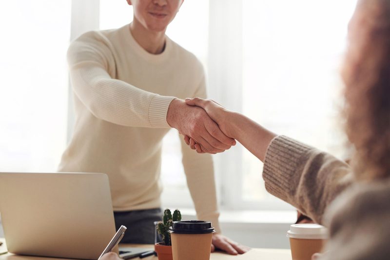 Hiring manager shaking hands with a candidate across a desk